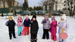 Dzieci stoją na śniegu na placu zabaw