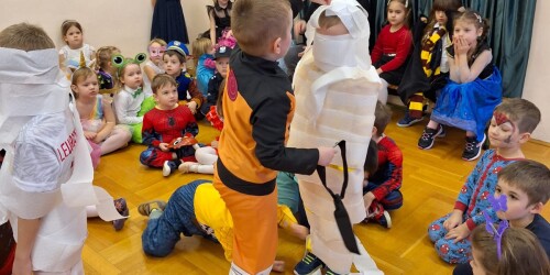 Dzieci biorą udział w konkurencji karnawałowej tworzenia stroju z papieru toaletowego