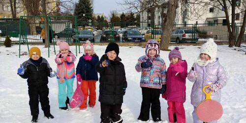 Dzieci stoją na śniegu na placu zabaw